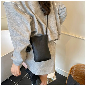 Detail of black mini crossbody phone bag with lychee grain texture and knotted strap