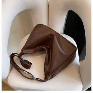 Gros plan d'un sac Hobo marron foncé avec texture litchi rétro sur chaise blanche