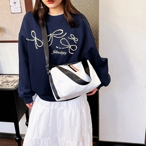 Sac bandoulière blanc en tissu Oxford avec sangle noire présenté sur un mannequin