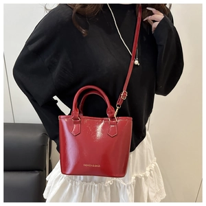 Detail of red patent leather bucket bag with top handles and fashion logo print