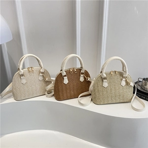 Tres bolsos de paja tejida en forma de concha en blanco, marrón y caqui con asas de cuero