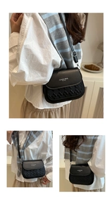 Detail of black crossbody bag featuring woven texture and Fashion Trend gold lettering
