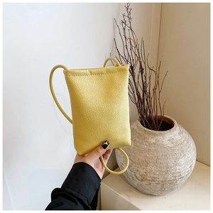 Close-up of a yellow mini crossbody phone bag with pebble leather texture and thin strap