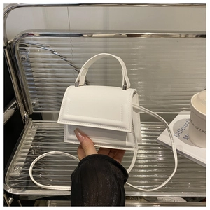 Detail of a minimalist white crossbody mini bag featuring fine PU leather texture and handle