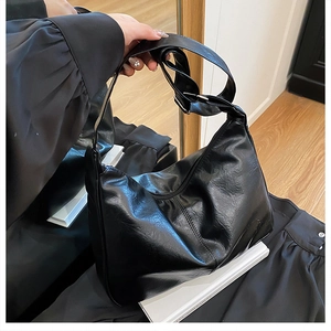 Détail du sac hobo en similicuir noir montrant la texture brillante et la boucle
