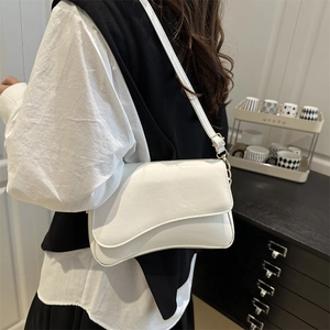 Glossy white patent leather shoulder bag with asymmetrical flap and gold hardware details