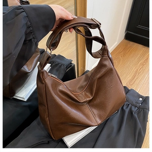 Gros plan du sac cabas en cuir PU marron avec texture vintage et bandoulière dans un reflet de miroir