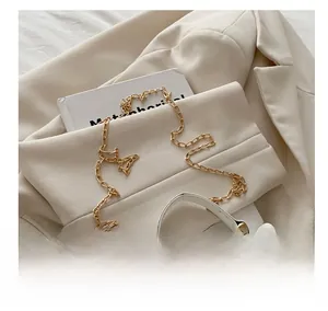 Detail view of gold chain strap and metallic lock on a white leather crossbody bag