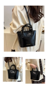 Détail du sac seau noir brillant avec logo doré et bandoulière réglable