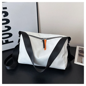 Detail of white nylon crossbody bag with black zippers and orange decorative pullers