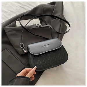 Detail of black crossbody bag featuring textured weave pattern and fashion trend lettering