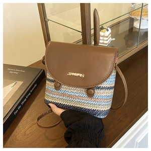 Détail du sac seau en paille tressée arc-en-ciel avec rabat en cuir et logo métallique