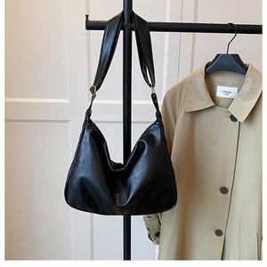 Détail d'un sac cabas noir en cuir huilé ciré montrant sa texture vintage et sa bandoulière