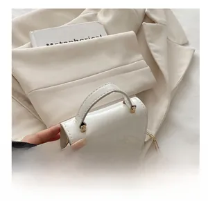 Detail showing the white patent leather handle and elegant gold chain strap on the bag