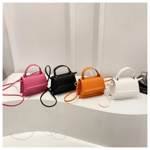 Detailed view of mini crossbody bags in pink, black, orange, and white faux leather