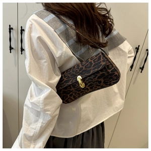 Detailed close-up of leopard print baguette bag featuring a gold horseshoe metal buckle