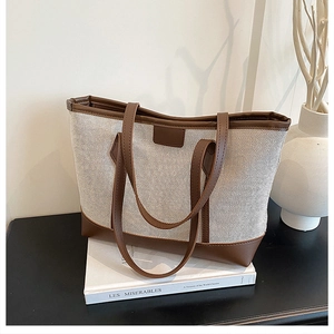 Detail of canvas tote bag with brown leather trim and handles on a minimalist background