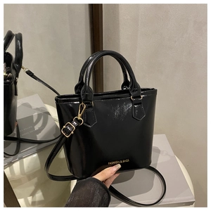 Détail du sac seau en cuir verni noir avec lettrage doré et bandoulière amovible