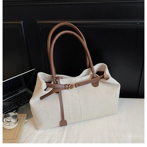 Detail of canvas tote bag texture with leather handle, laptop and books on desk