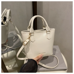 Détail du sac seau en cuir crème avec poignées, bandoulière et finitions dorées chic