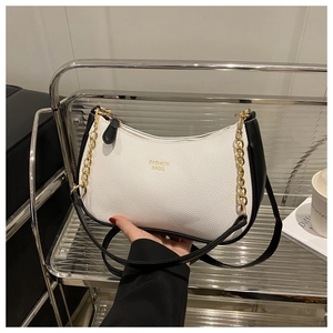 Detail of lychee pattern leather texture on black and white tote with gold chain strap