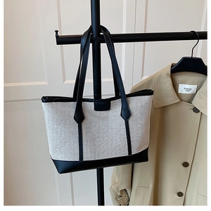Close-up of beige canvas tote bag with black leather reinforced base and double handles