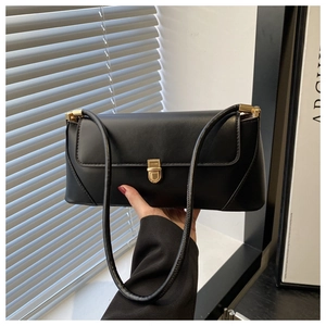 Close-up of minimalist black matte leather shoulder bag with a polished gold metal clasp