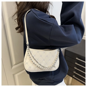 Detail of off-white quilted shoulder bag with silver chain and pearl strap decoration