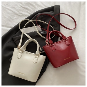 Détail du sac seau minimaliste en crème et bordeaux avec finition brillante et logo