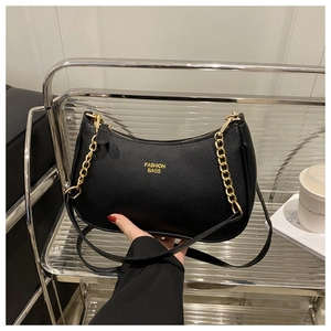 Detail of black pebbled leather hobo bag with gold chain and printed fashion text