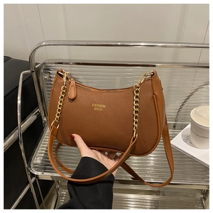 Detail of caramel lychee grain leather crescent bag with decorative gold chain and strap