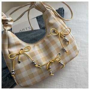 Detail of yellow gingham shoulder bag featuring dainty bow accents and silver beads