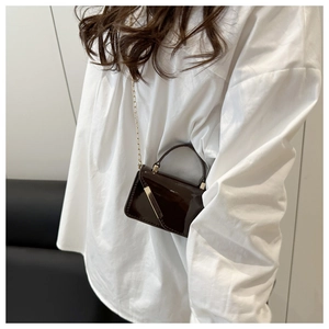 Close-up of a glossy burgundy patent leather mini chain bag with elegant gold hardware detail
