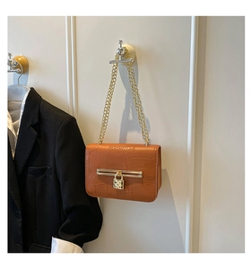 Detail of caramel brown crocodile embossed texture and gold lock hardware on crossbody bag
