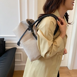 Linen patchwork tote bag with black leather straps and gold buckle worn by model