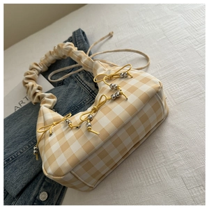 Close-up of yellow plaid underarm bag with pleated handle and bow knot detail