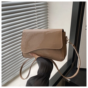 Detail of glossy beige patent leather bag with unique wavy edge flap and slim strap