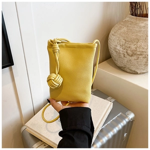 Detail of yellow lychee texture phone bag with minimalist oversized knot shoulder strap