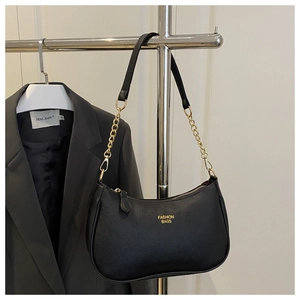 Detail of black pebbled leather texture with gold lettering and metal chain strap