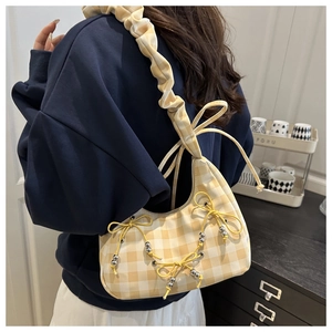 Detailed side view of yellow plaid crescent bag with decorative bows and beaded straps