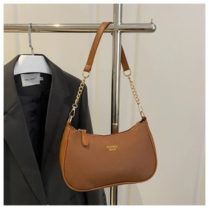 Detailed shot of brown litchi pattern leather bag with gold chain on a silver rack