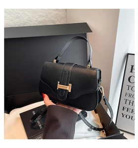 Close-up of black lychee grain leather bag featuring a gold H-shaped metal buckle
