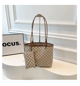 Detail of checkered brown tote bag set with matching coin purse on minimalist pedestal