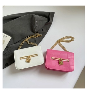 Close-up of white and pink faux crocodile leather handbags with gold chain and metal lock