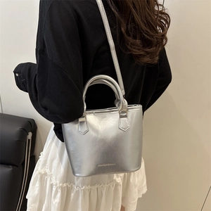 Sac seau métallisé argenté avec poignée et bandoulière présenté dans un cadre fashion