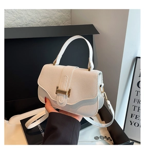 Detail of white lychee leather handbag with golden H-clasp and elegant hand-held strap