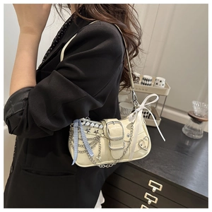 Detail of cream shoulder bag with silver chains, star studs and decorative bow accents