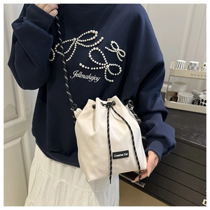 Détail du sac seau blanc à cordon avec étiquette Creative Cat et bandoulière tissée
