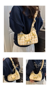 Detail showing yellow plaid fabric, decorative ribbon bows, and ruched shoulder strap