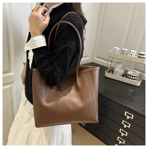 Detailed close-up of a brown leather tote bag with reinforced stitching on the shoulder strap